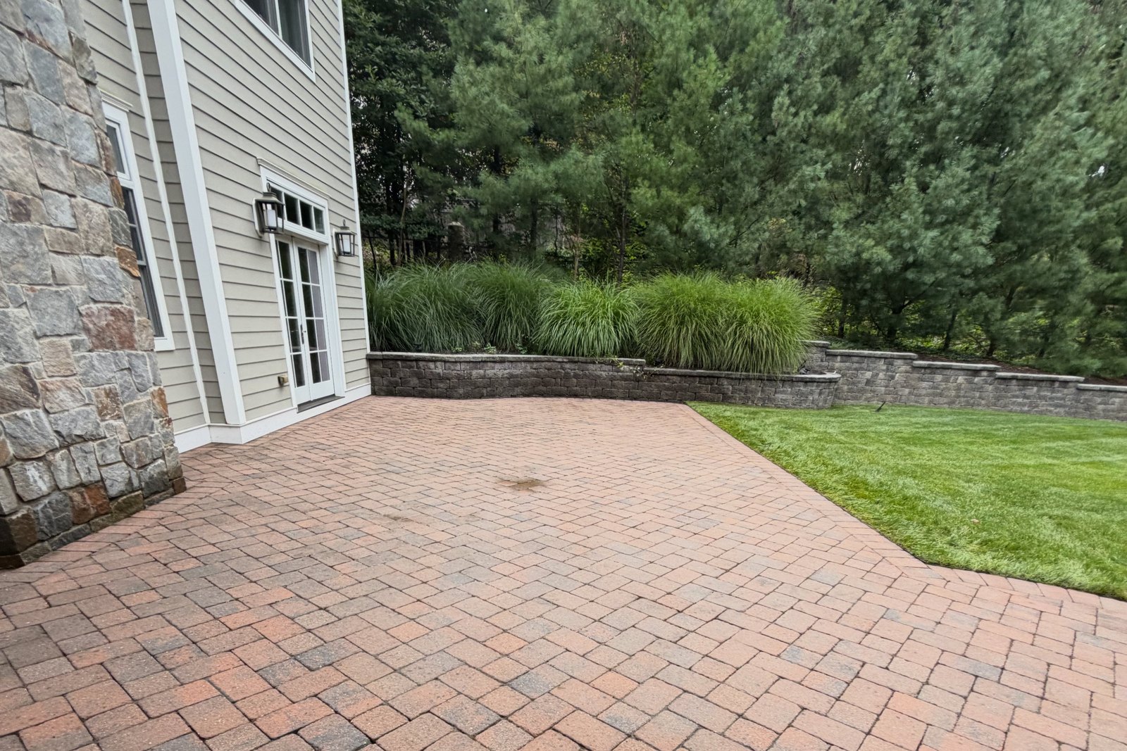 The same backyard patio after pressure washing, pavers restored to warm brick
